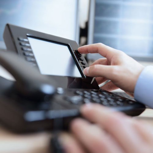 A person is using the phone on a desk.