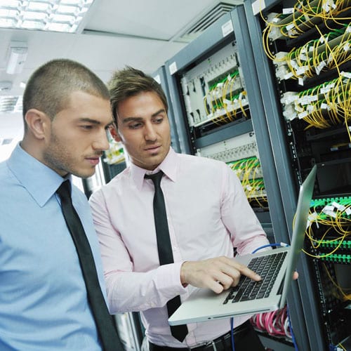 Two men looking at a laptop in an aisle.