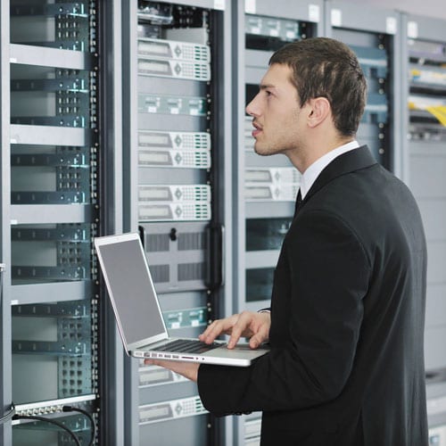 A man in suit and tie holding a laptop.