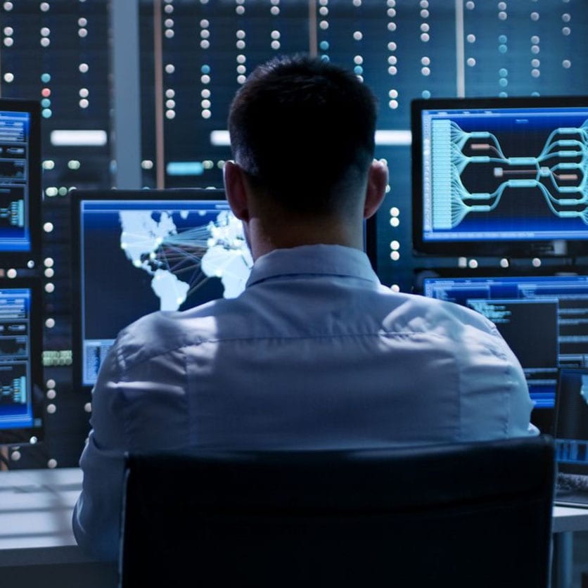 A man sitting in front of multiple computer screens.