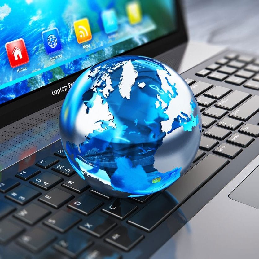 A globe sitting on top of a laptop keyboard.